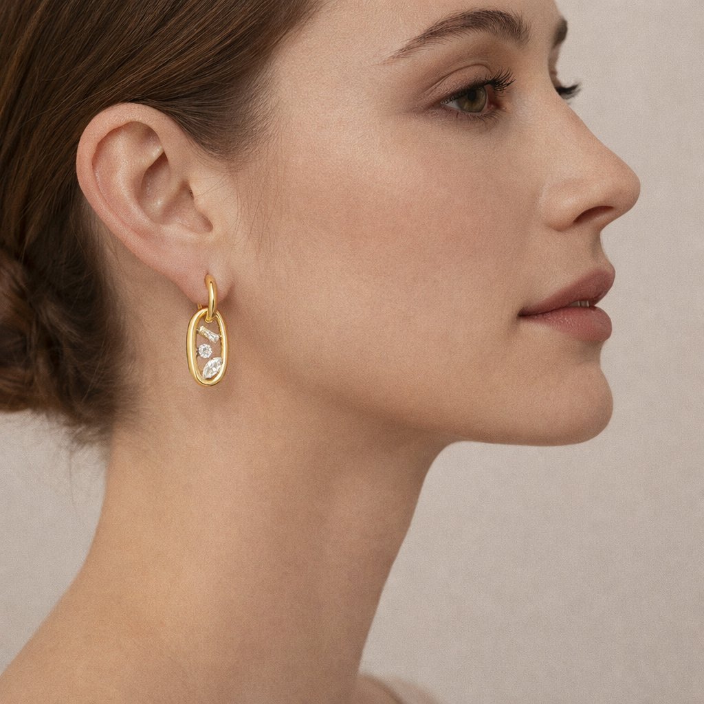 In profile, the Astral EARRINGS show their crystal-set oval link swinging gently from a small gold hoop.