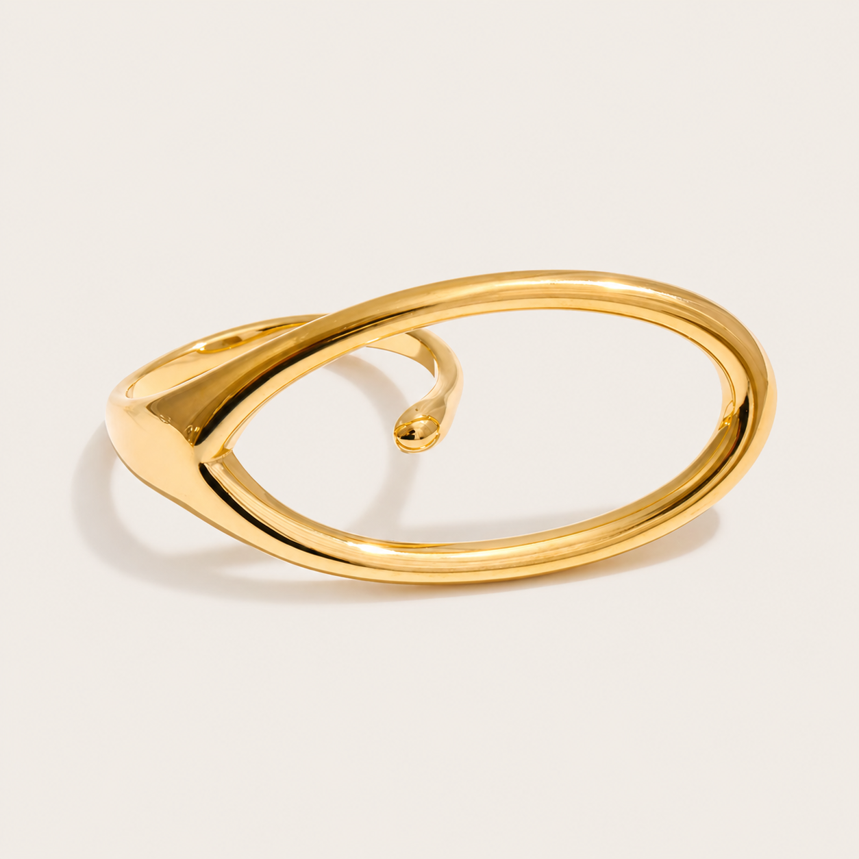 Gold ring with a large open oval loop curving into a slim pointed band, shown in close-up on a cream backdrop — Folie à Trois Aura RING.