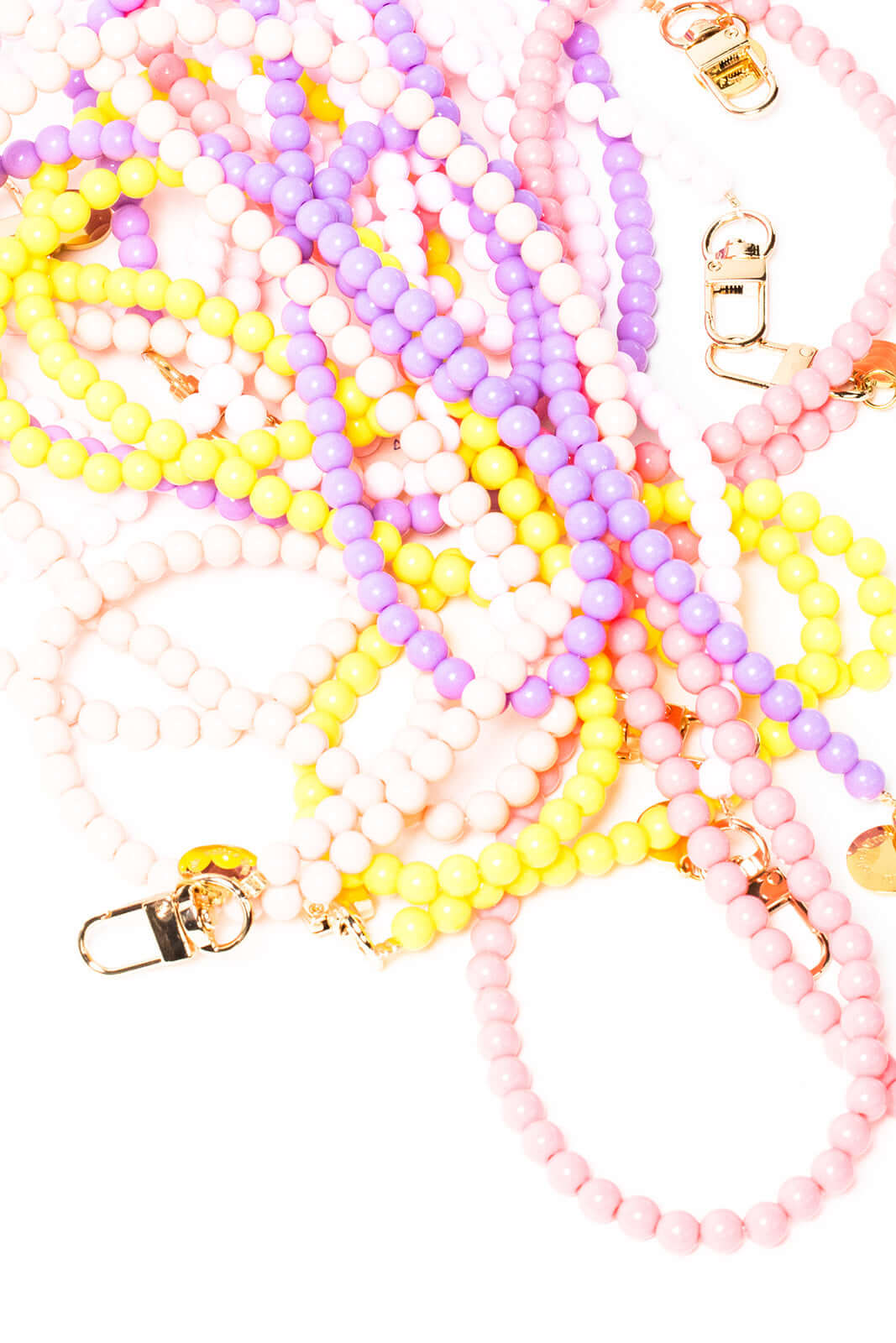 Overhead view of several Aurora PHONE CORD strands in pink, purple, yellow, white and lavender beads tangled together.