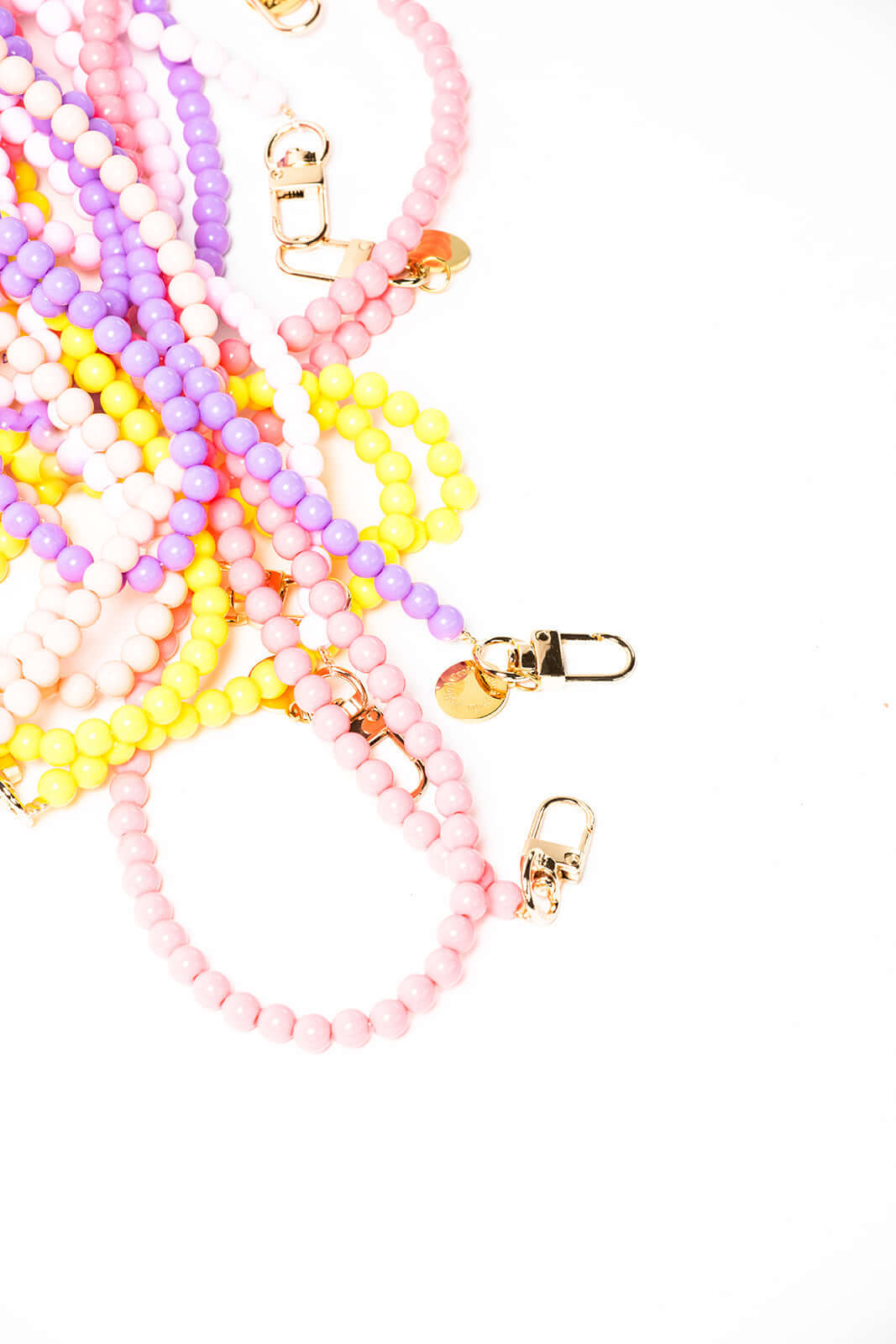 Angled close-up of tangled pink, yellow, lavender and white beaded Aurora PHONE CORD strands with clasps.
