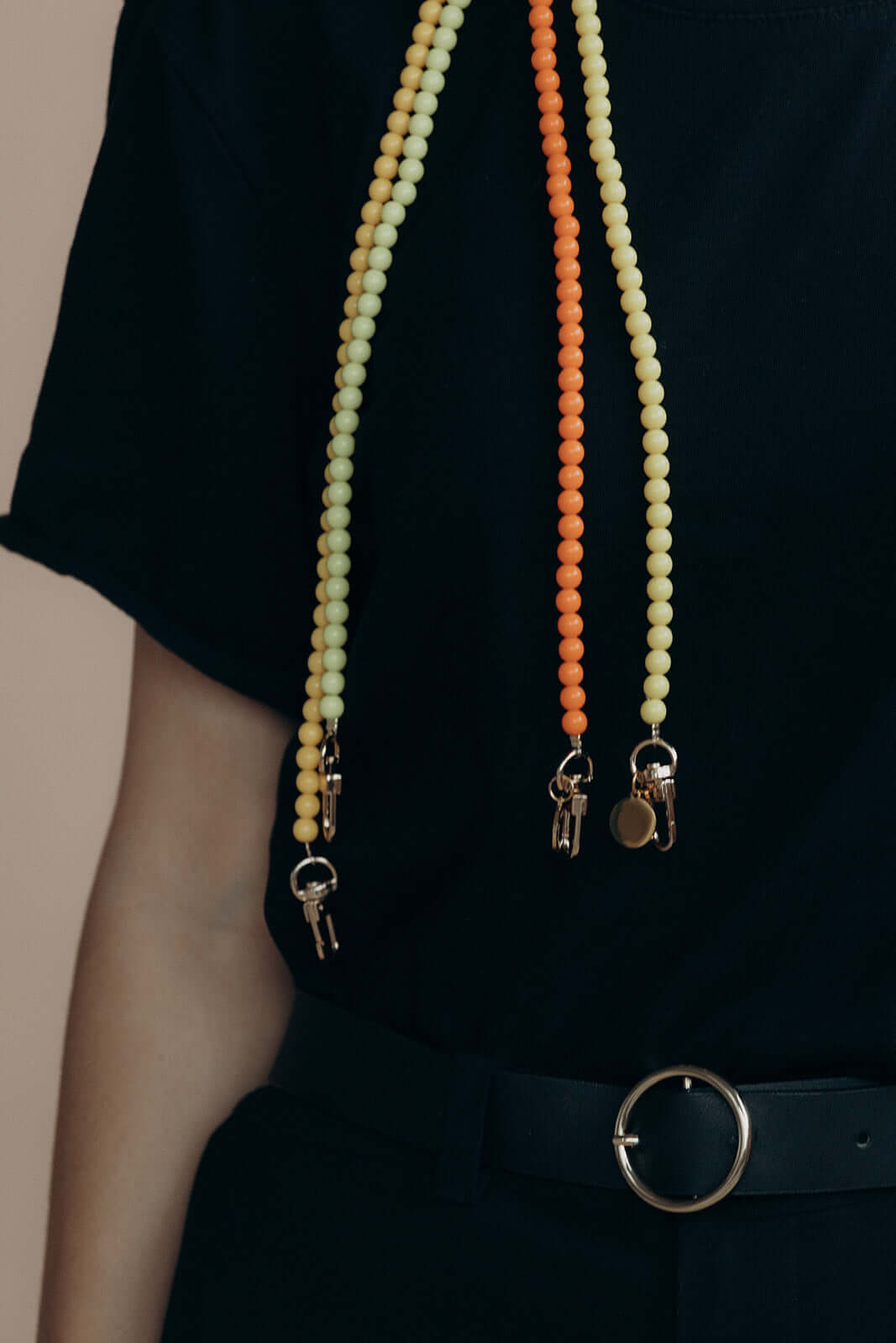 Model wearing pale yellow and orange beaded Aurora PHONE CORD strands with keys clipped on, over a black outfit.
