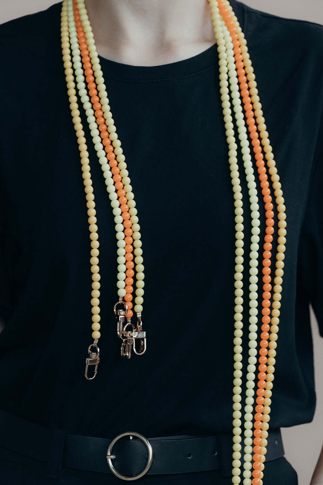 Model wearing pale yellow and orange beaded Aurora PHONE CORD strands hanging down the front of a black top.