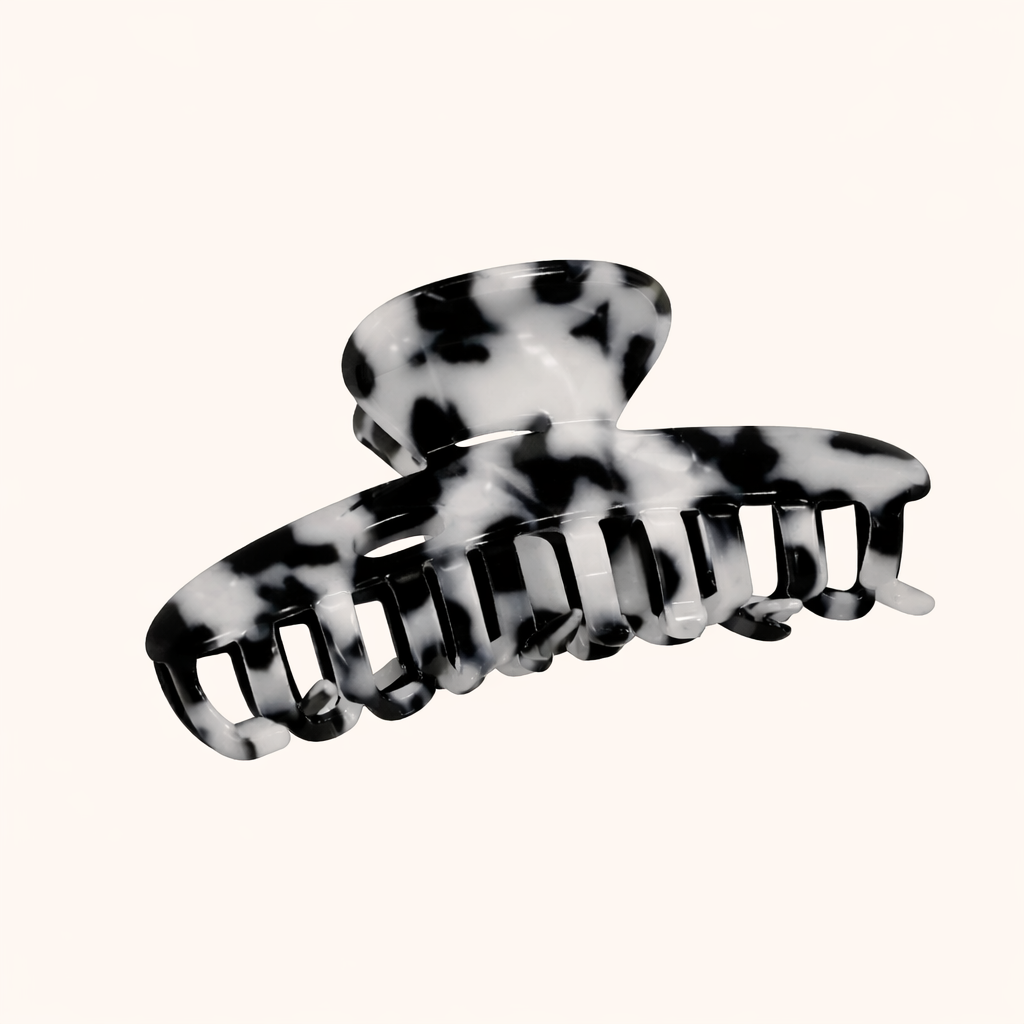 Black and white dalmatian-print acetate claw clip from the Baby Love HAIR CLIP collection, shown on a cream studio background.