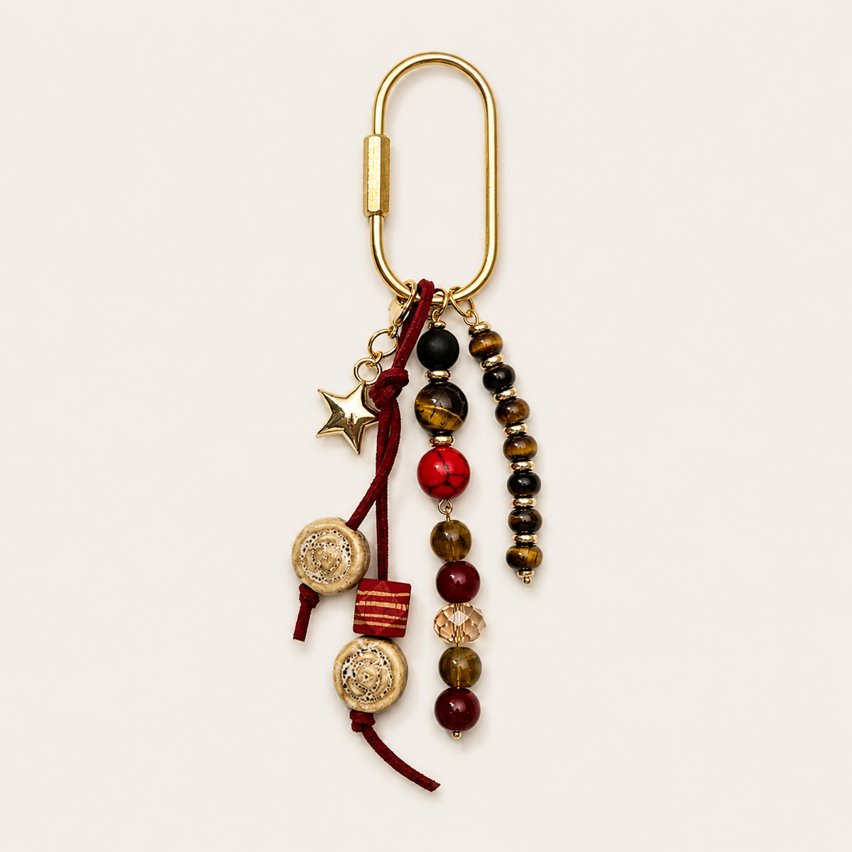Folie à Trois Bahia BAG CHARM with tiger's eye and burgundy beaded strands, wood beads, and a gold star charm on a gold clasp.