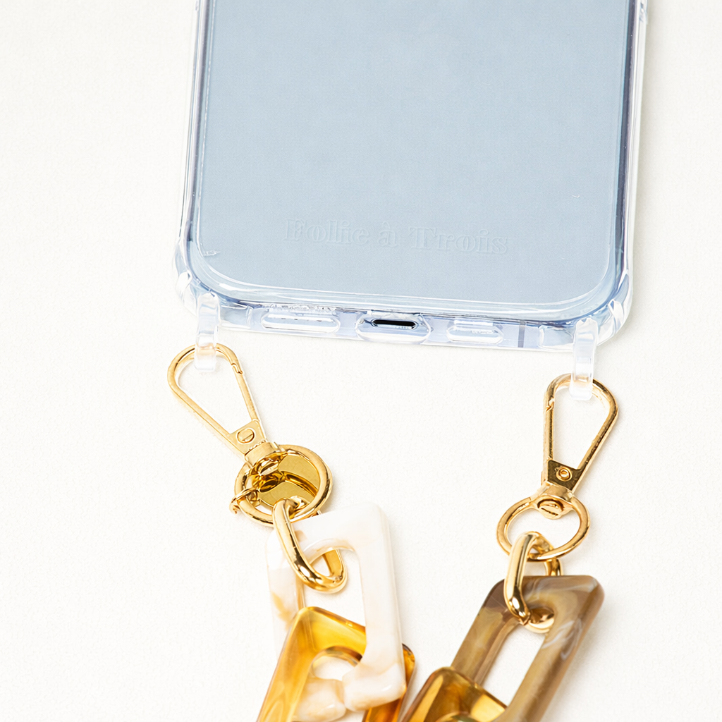 Close-up of the amber tortoise acrylic Bennie chain clipped to a clear phone case.