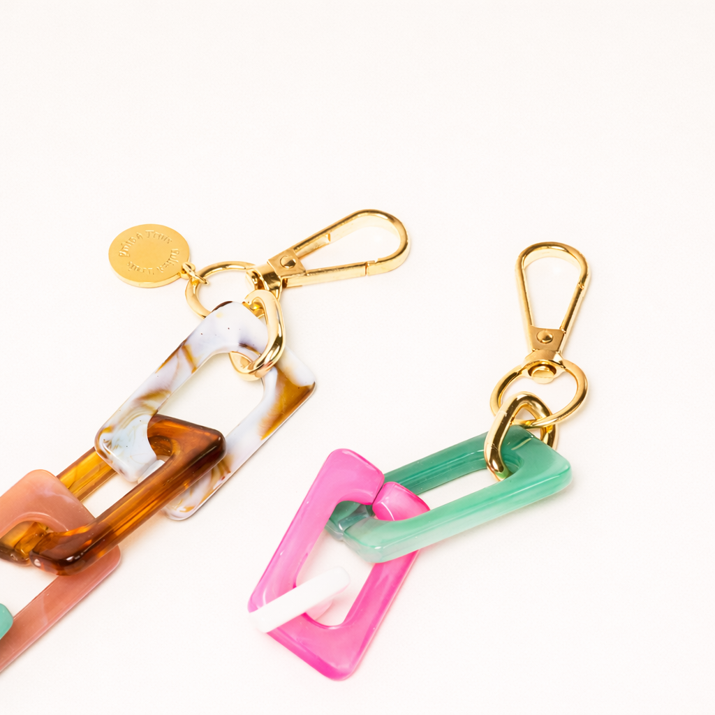 Close-up of the gold clasp ends on the tortoise, white, pink, and teal acrylic Bennie chain.