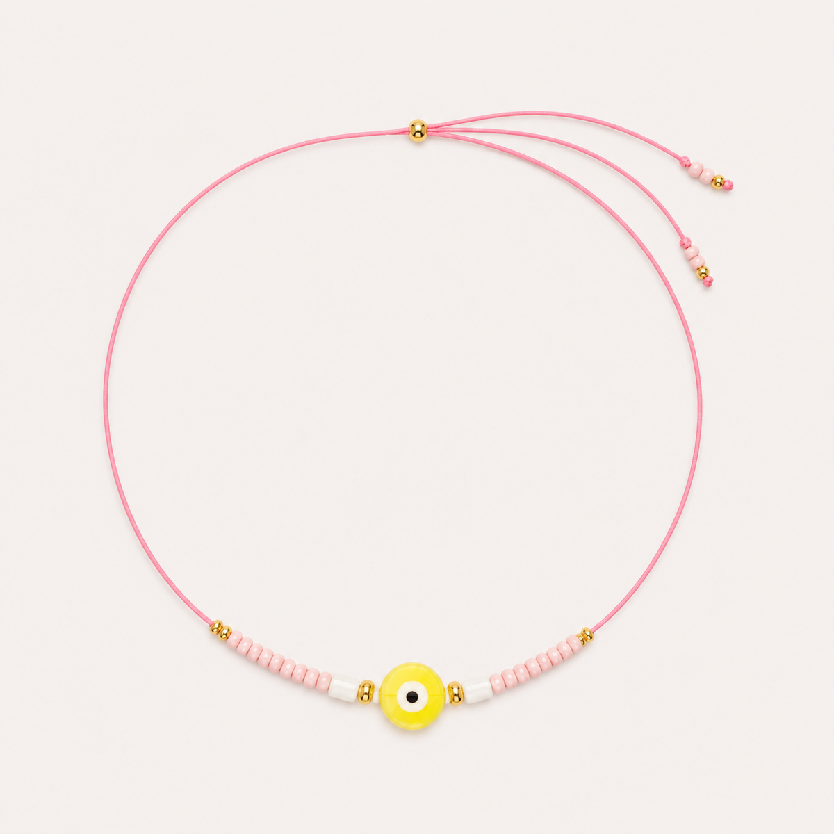 Pink cord Big Eye NECKLACE with beaded pink and white accents around a yellow enamel evil eye charm, laid flat.