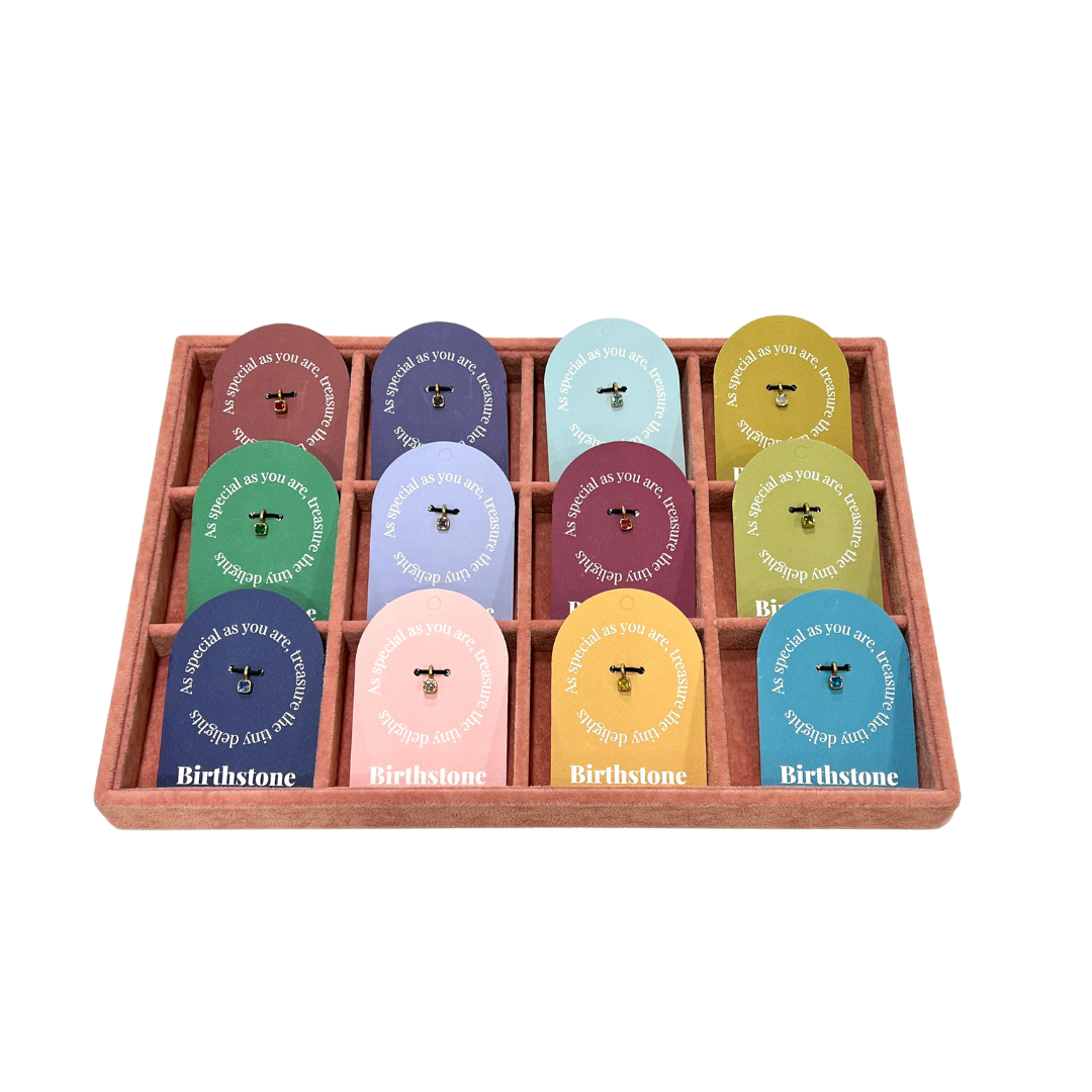 The Birthstone Charm BUNDLE in a black tray holding all twelve monthly Birthstone gift tag cards, each with its gold charm attached.