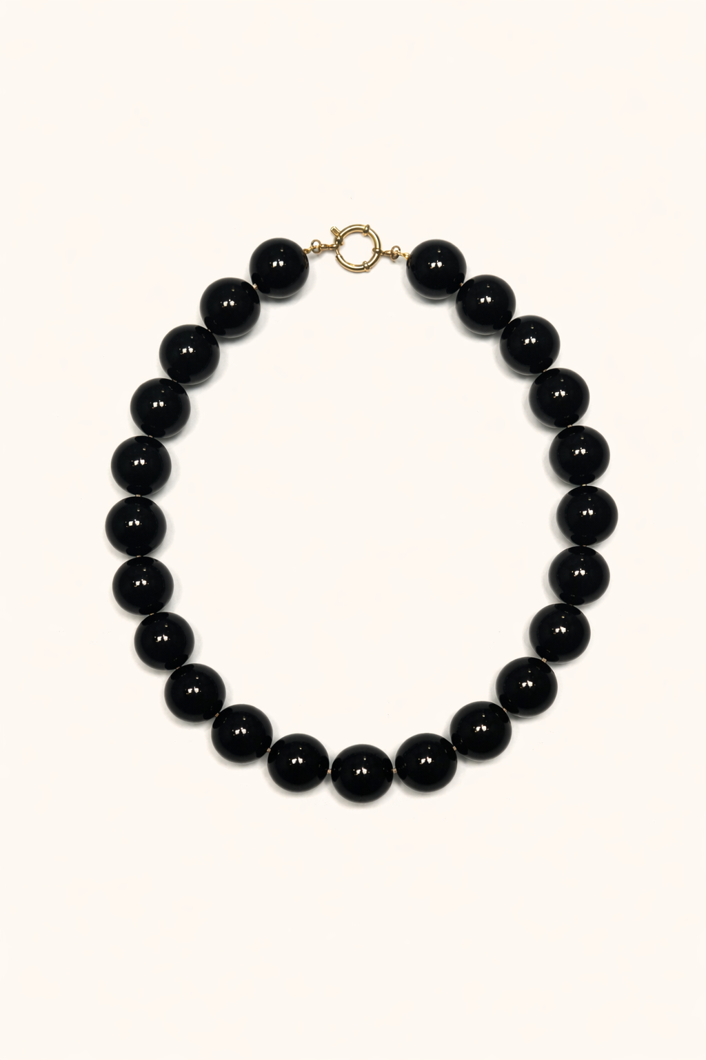 The Blaire NECKLACE in black, a single strand of large glossy round beads with a gold ring clasp, shown flat.