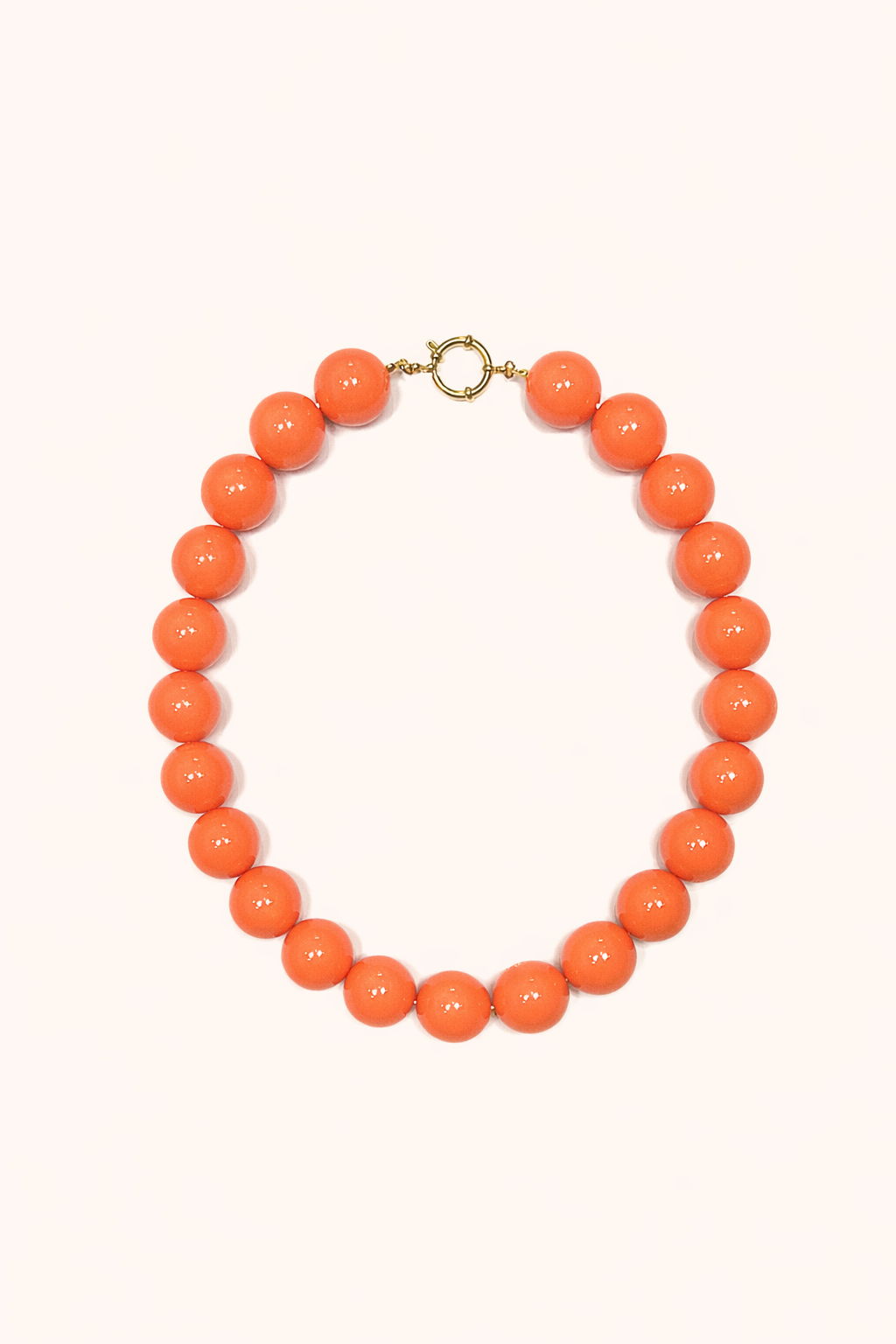 The Blaire NECKLACE in coral, a single strand of large glossy round beads with a gold ring clasp, shown flat.