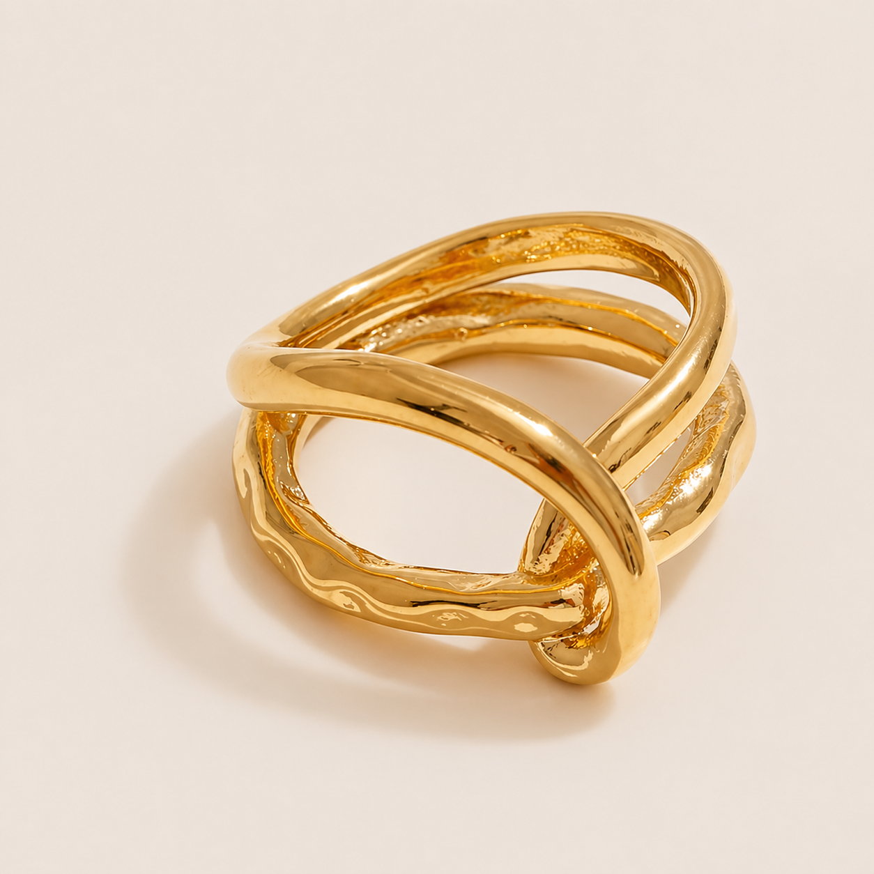 Gold ring with multiple wavy, twisted bands layered and crossing over each other, on a cream backdrop — Folie à Trois Blaze RING.
