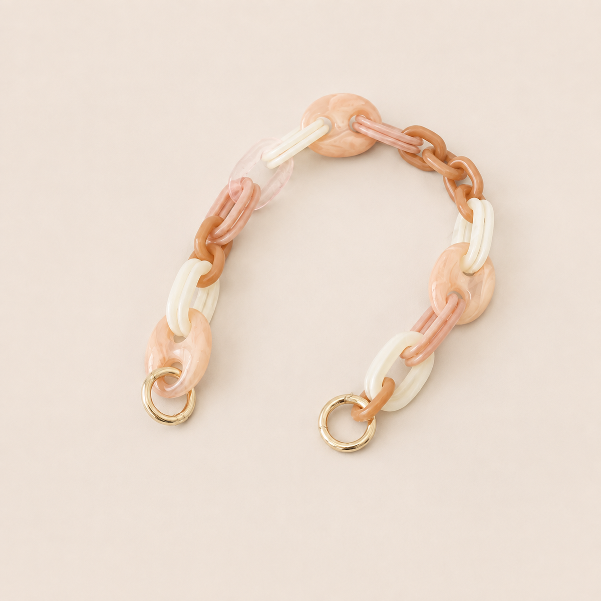 Folie à Trois Bracken short phone chain in pink, tan and white marbled links with gold clasps, laid flat on a cream background.
