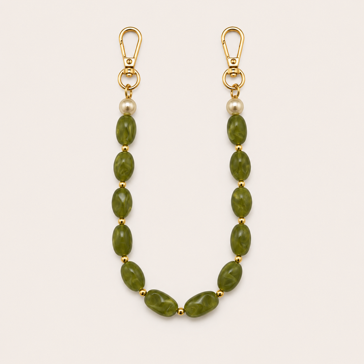 Folie à Trois Briar short wholesale phone chain in green marbled nugget beads with pearl accents and gold clasps, laid flat on a cream background.