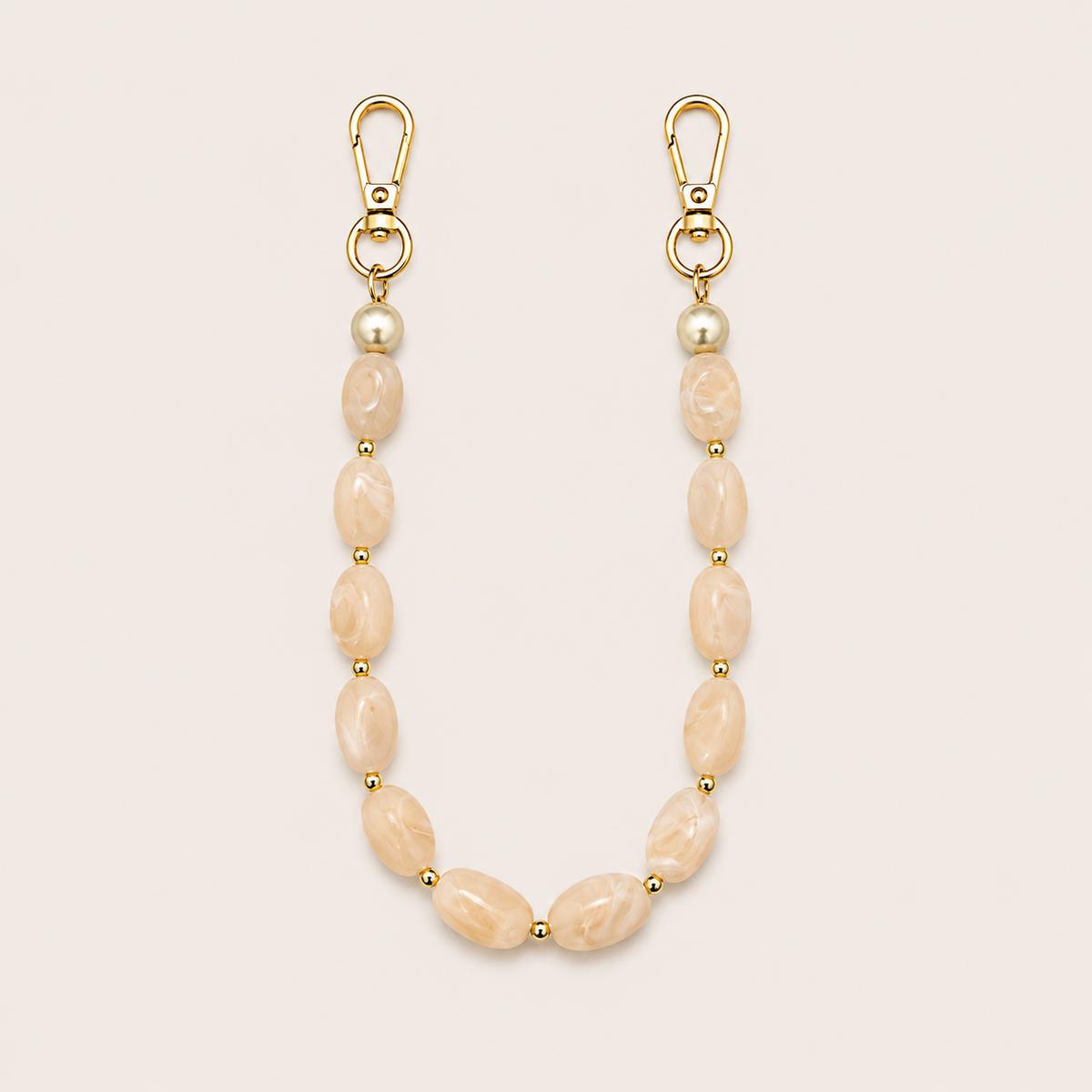 Folie à Trois Briar short wholesale phone chain in beige marbled nugget beads with pearl accents and gold clasps, laid flat on a cream background.