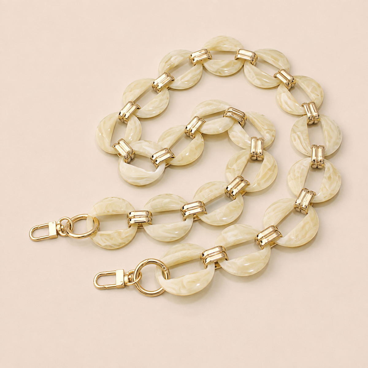Cream marbled resin link phone chain with gold connectors coiled on cream — Folie à Trois Cedar wholesale phone chain