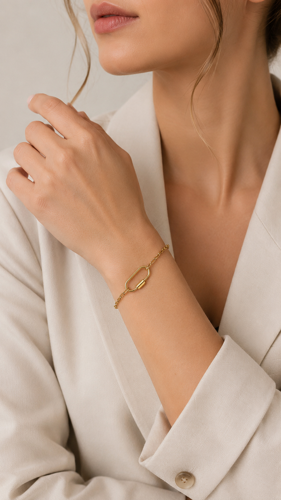 Chain link Charm BRACELET worn on the wrist, the oval carabiner clasp visible, model in a cream blazer.