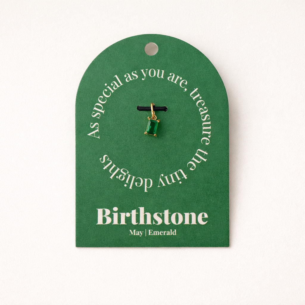 The Classic Drop Birthstone Charm in green emerald hangs from a black cord on a green gift card reading Birthstone, May, Emerald.