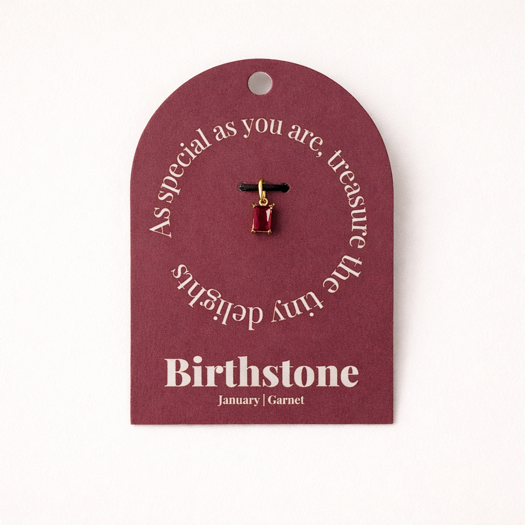 The Classic Drop Birthstone Charm in deep red garnet hangs from a black cord on a burgundy card reading Birthstone, January, Garnet.