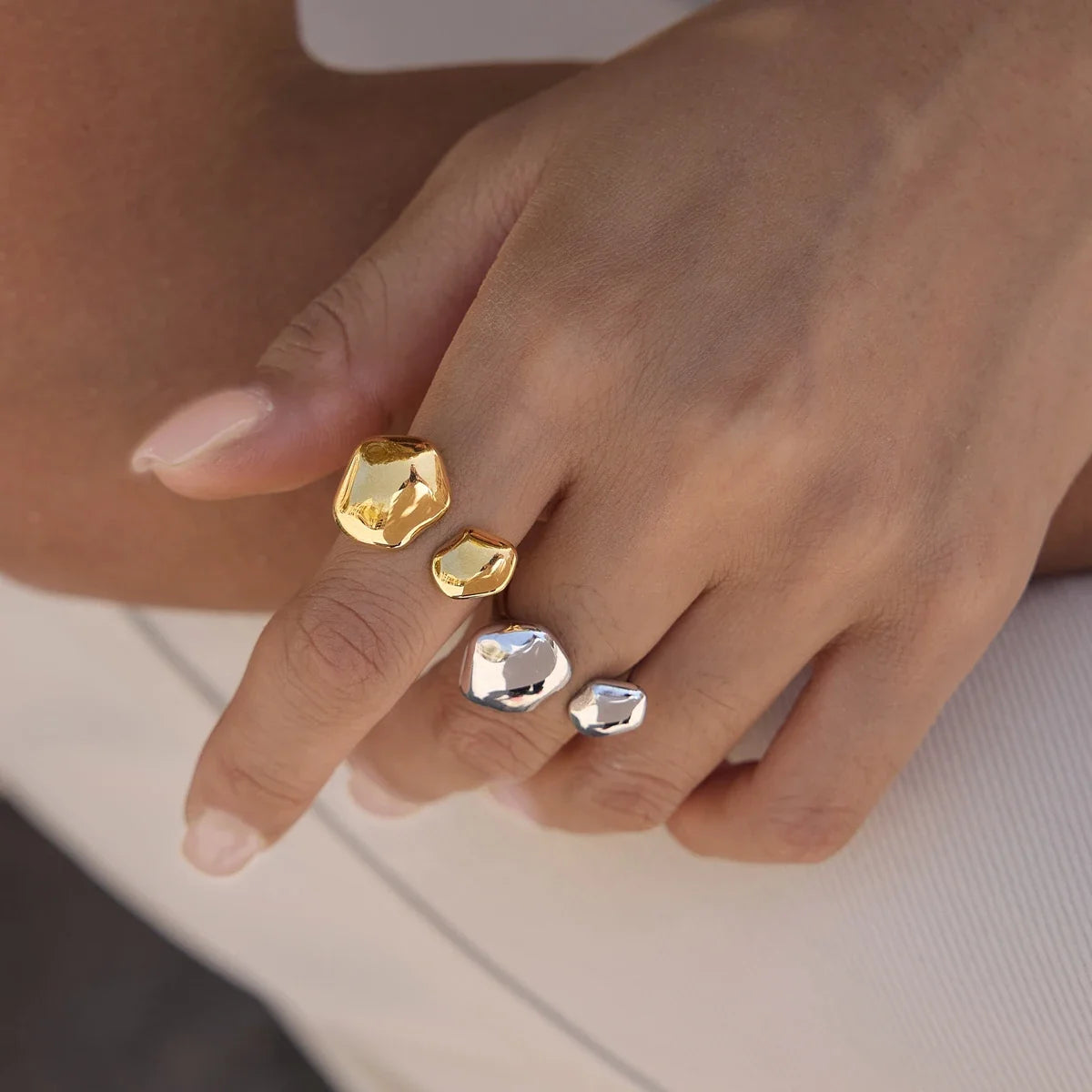 Hand wearing gold and silver-tone Cloud RINGS with organic pebble shapes, stacked on two fingers — Folie à Trois