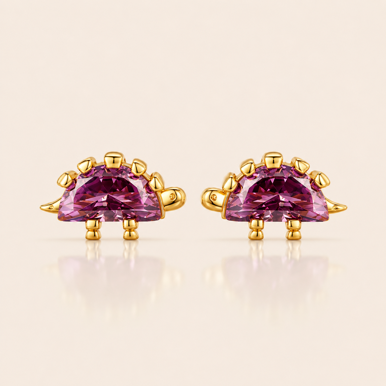 Gold stegosaurus-shaped stud earrings from the Colorful Dino EARRINGS with a purple half-moon cubic zirconia body and spiked back.