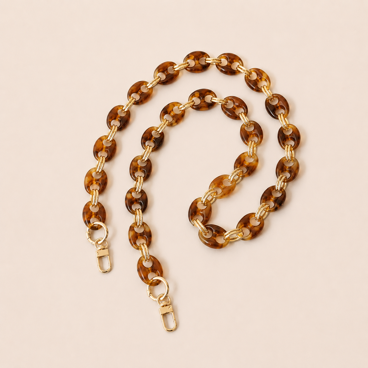 Light brown tortoiseshell coin-link phone chain with gold connectors coiled on cream — Folie à Trois Corvin long phone chain