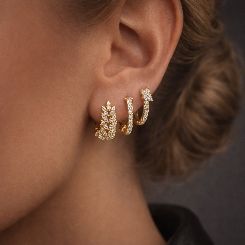 Daisy Set worn on the ear in gold, three pave hoops stacked with a leaf shape and graduated crystal accents.