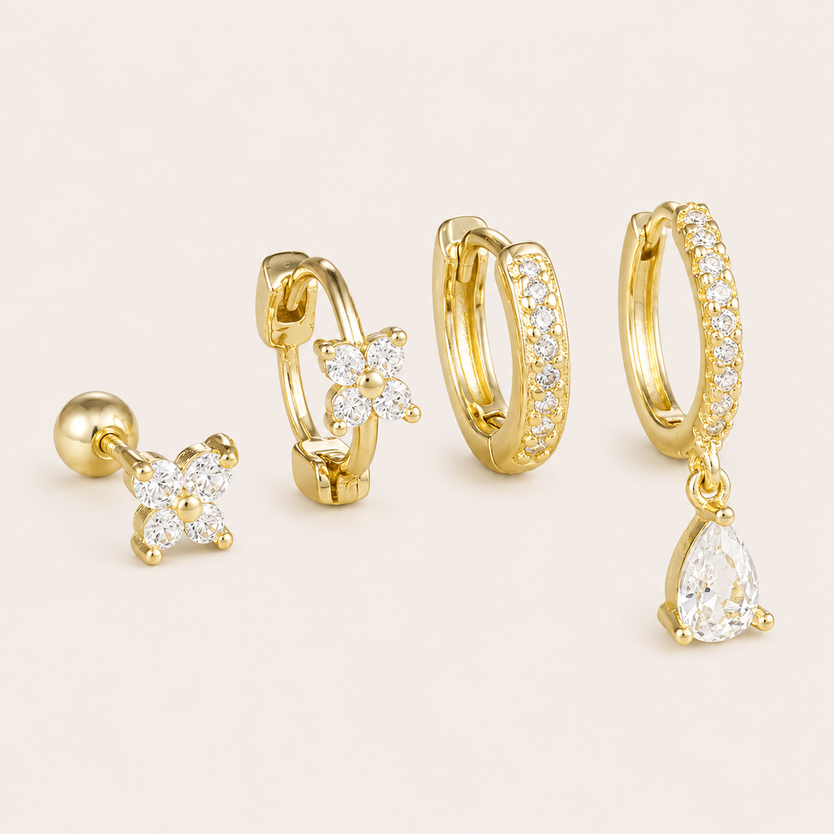 Four-piece Deanna SET gold earrings in clear stones: a flower stud, a flower hoop, a pave hoop, and a hoop with a pear-cut drop charm.