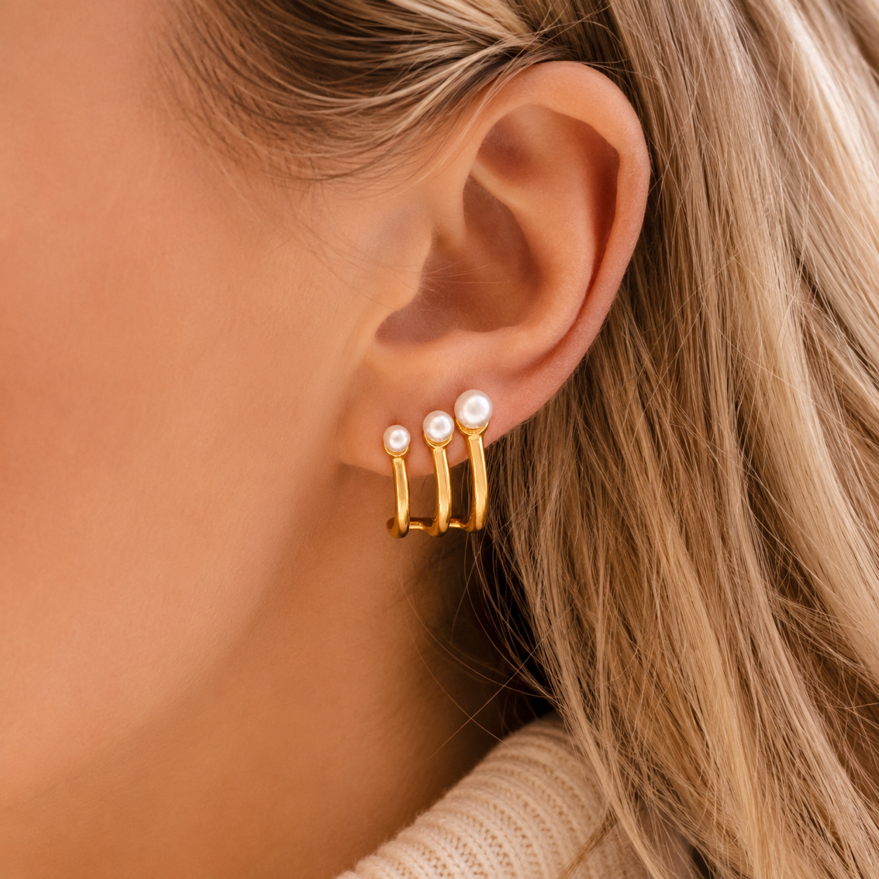 Effie Earrings worn on the ear, three gold prongs tipped with small pearls curving along the lobe for a modern jacket look.