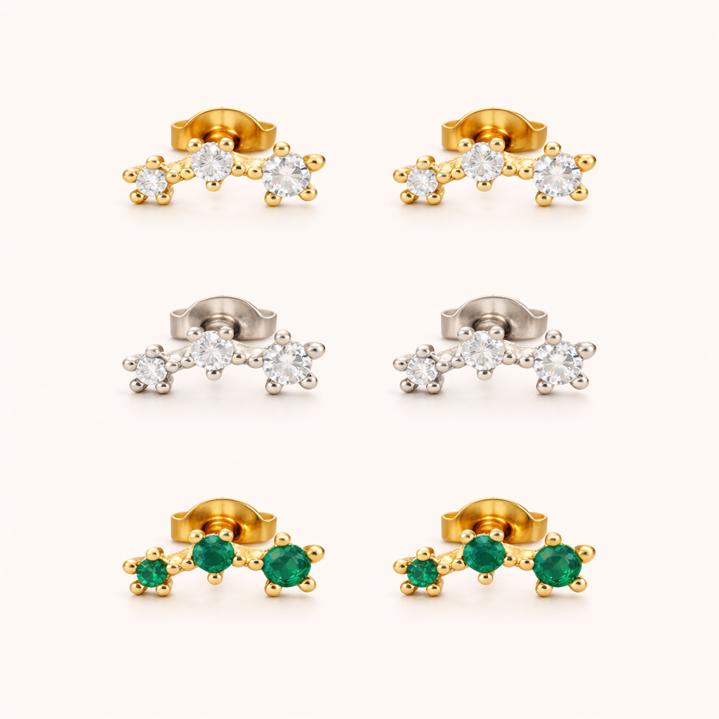 Three-stone climber earrings shown together in gold, silver, and emerald-green colorways, each set with a graduated row of round stones.