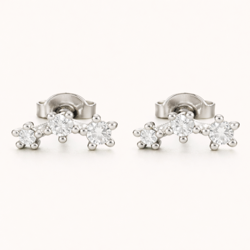 Silver three-stone climber earrings with graduated round clear stones set in a gently curved row, shown as a matching pair.