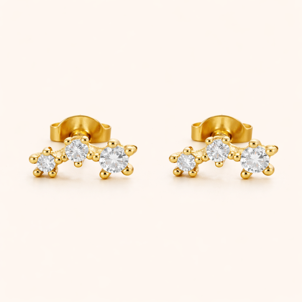 Gold climber earrings with three graduated round clear stones set in a curved row, shown as a matching pair, Elisa style.