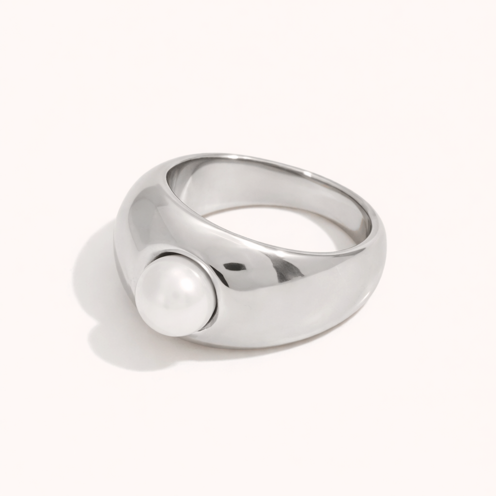 Chunky silver dome ring set with a single pearl, shown at an angle on a cream backdrop — Elka RING.