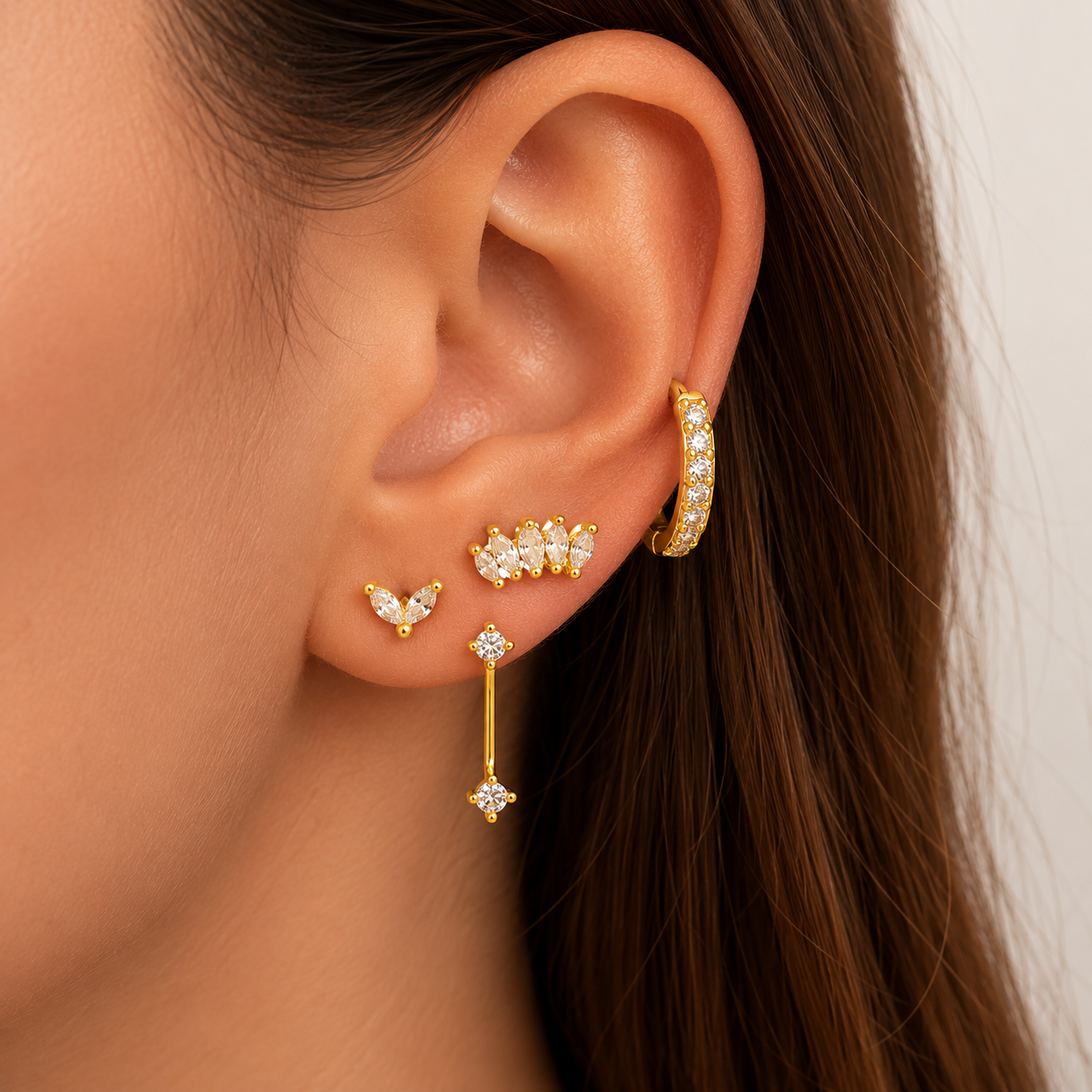 Elodie Set worn on the ear, layering marquise studs, a dangling crystal drop, and a pave huggie hoop along the lobe and cartilage.