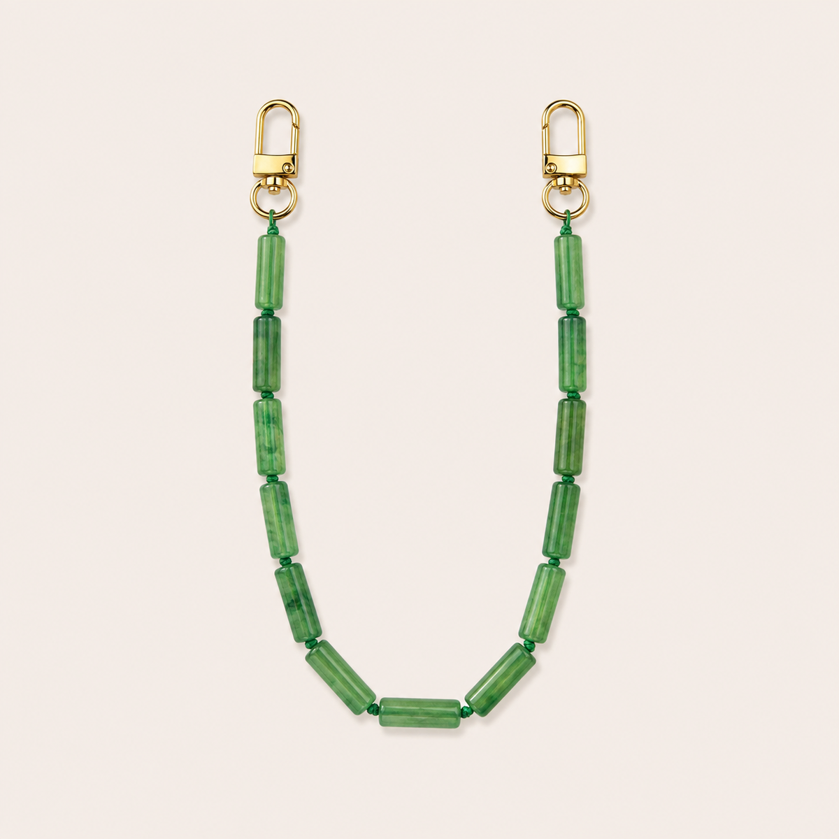 Kelly green tube-bead phone chain with gold lobster clasps laid flat on cream — Folie à Trois Elowen wholesale phone chain