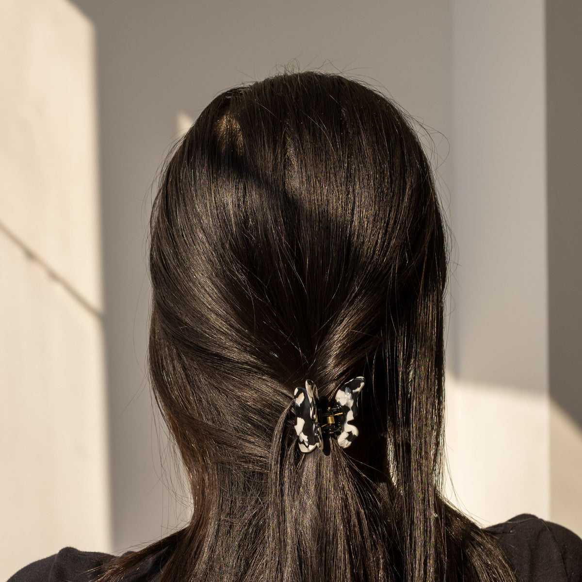 Falling For You Butterfly HAIR CLIP's black and white cow-print clip worn in dark hair, close-up view.