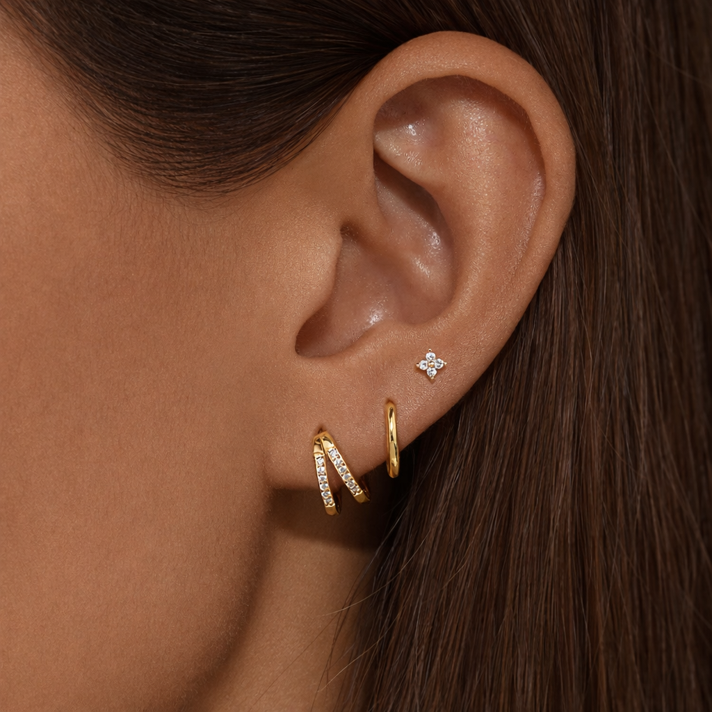 Faye Set worn on the ear, a pave crossover hoop and plain huggie hoop paired with a sparkling four-point stud.