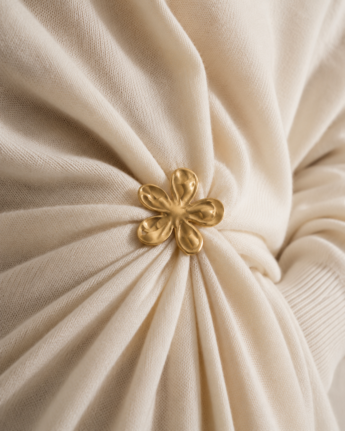 Close-up of a gold Flora BROOCH cinching draped cream knit fabric — Folie à Trois