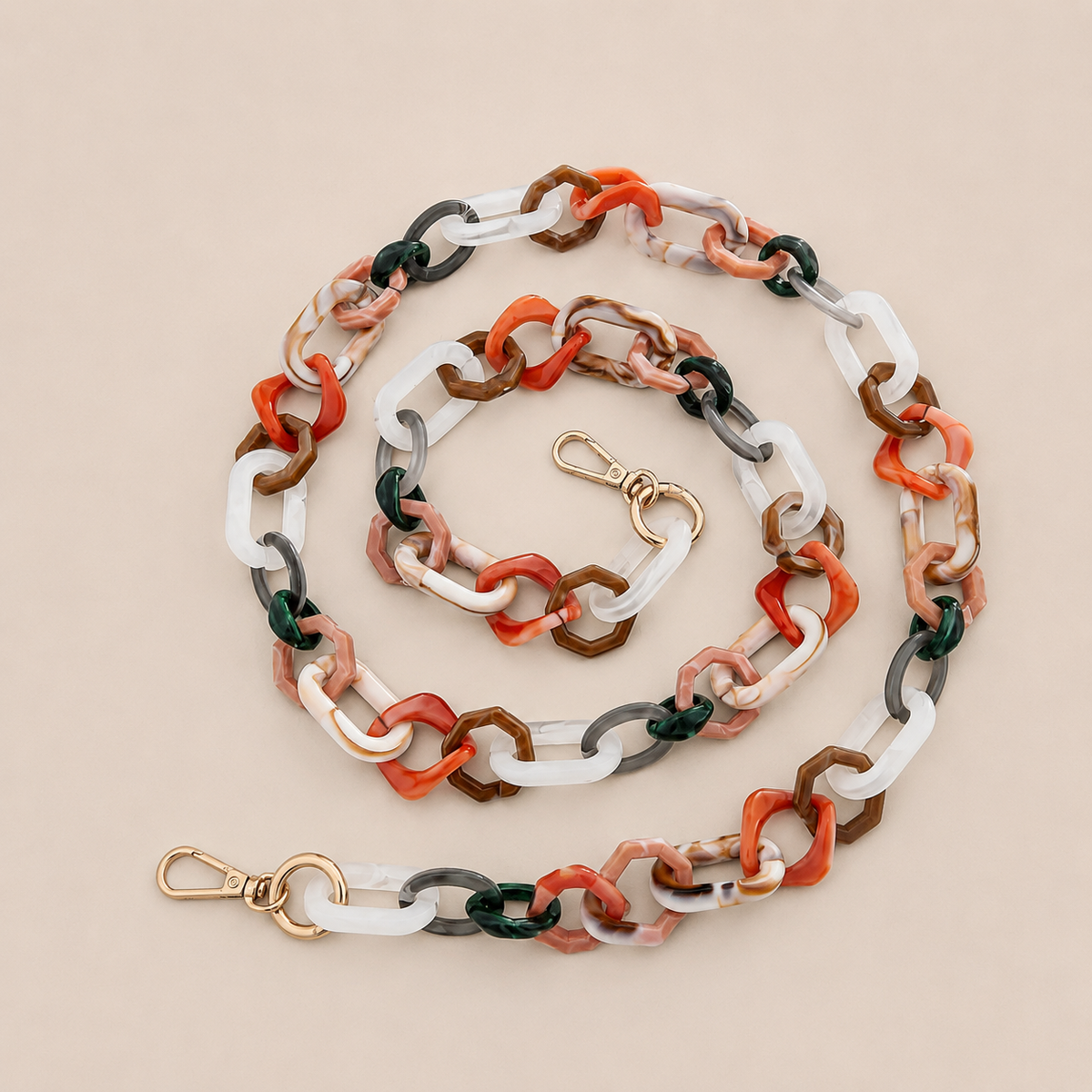 Folie à Trois Frost long phone chain in rust, white, dark green and tan marbled links with gold clasps, coiled on a cream background.