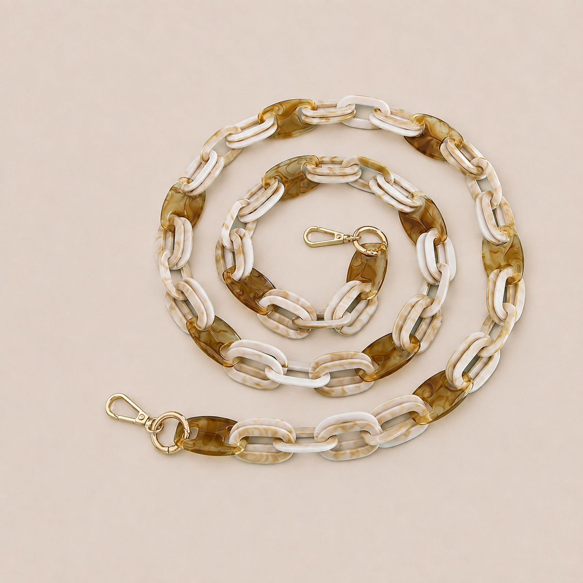 Folie à Trois Frost long phone chain in white and tan marbled links with gold clasps, coiled on a cream background.
