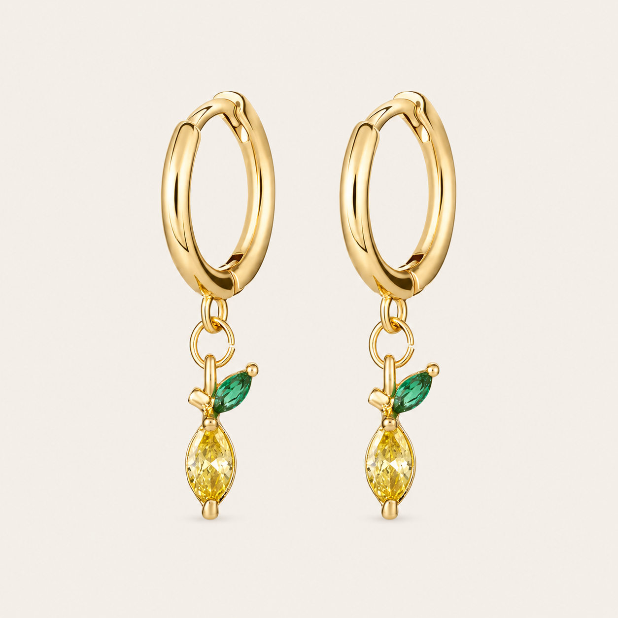 Gold huggie hoop earrings from the Fruit Hoop EARRINGS with a yellow marquise cubic zirconia charm and a green leaf accent, evoking a lemon.