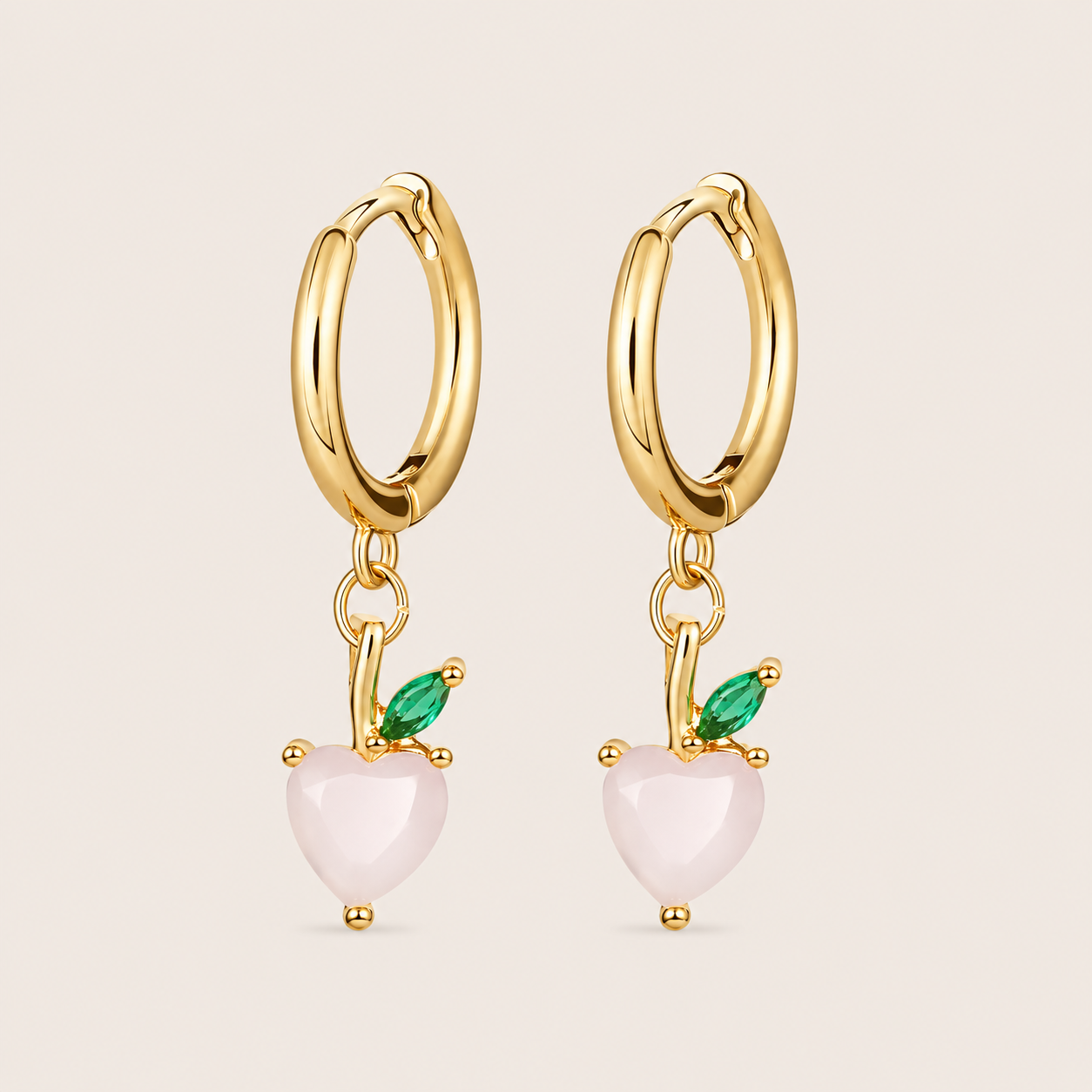 Gold hoop earrings from the Fruit Hoop EARRINGS with a peach-inspired charm in a pale pink heart-shaped stone and a green marquise leaf.