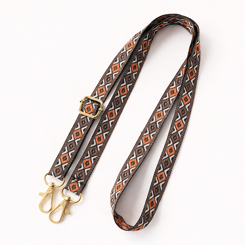 Woven Getaway long phone strap in brown and burnt-orange Aztec pattern, coiled flat with gold clasps.