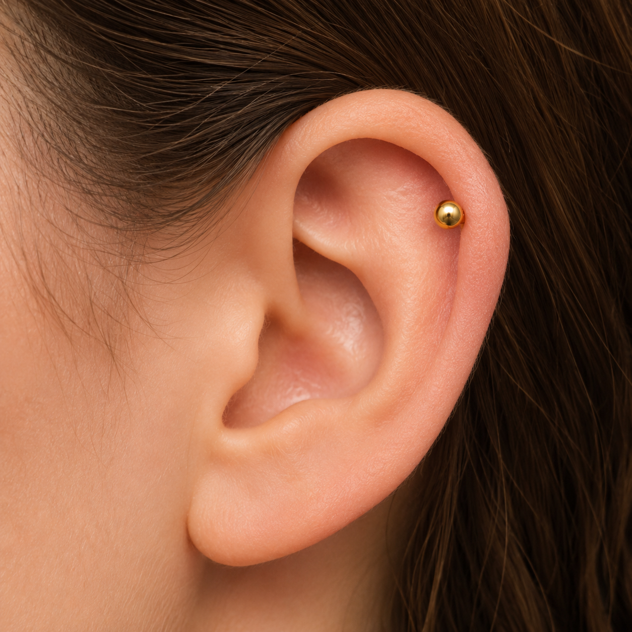 Worn in the cartilage, Glitz And Glam Piercing shows its small gold ball sitting neatly at the upper ear.