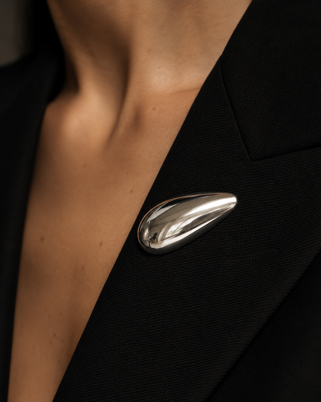Close-up of a silver teardrop Gota BROOCH pinned to the lapel of a black blazer — Folie à Trois