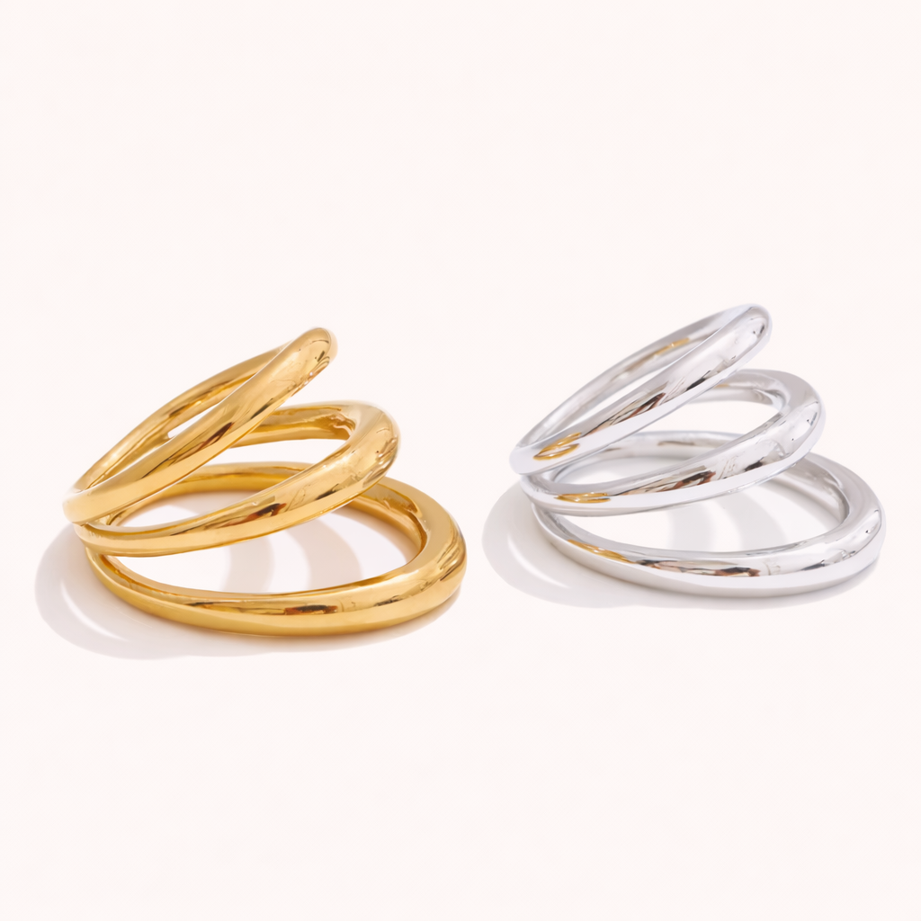 Gold and silver Harley RING styles, each with three interlocking smooth bands, shown together on a cream backdrop.