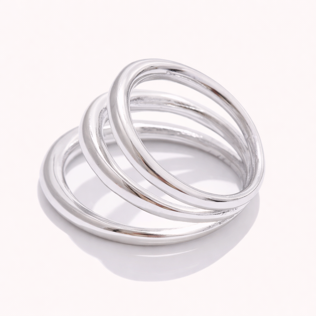 Silver Harley RING with three interlocking smooth bands, shown at an angle on a cream backdrop.