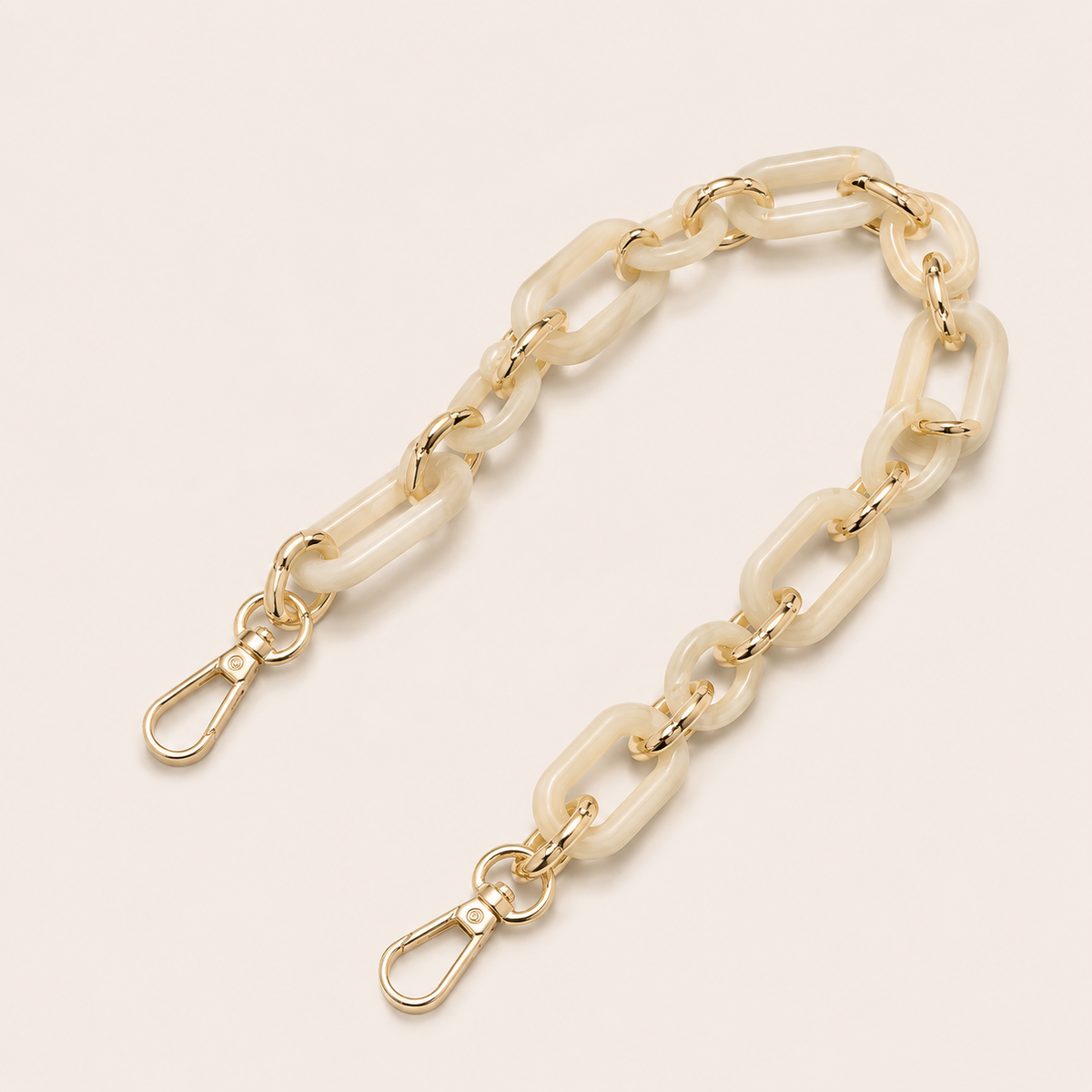 The Hazel SHORT PHONE CHAIN in ivory rectangular-link acrylic with gold-tone lobster clasp ends, curved on a light beige background.