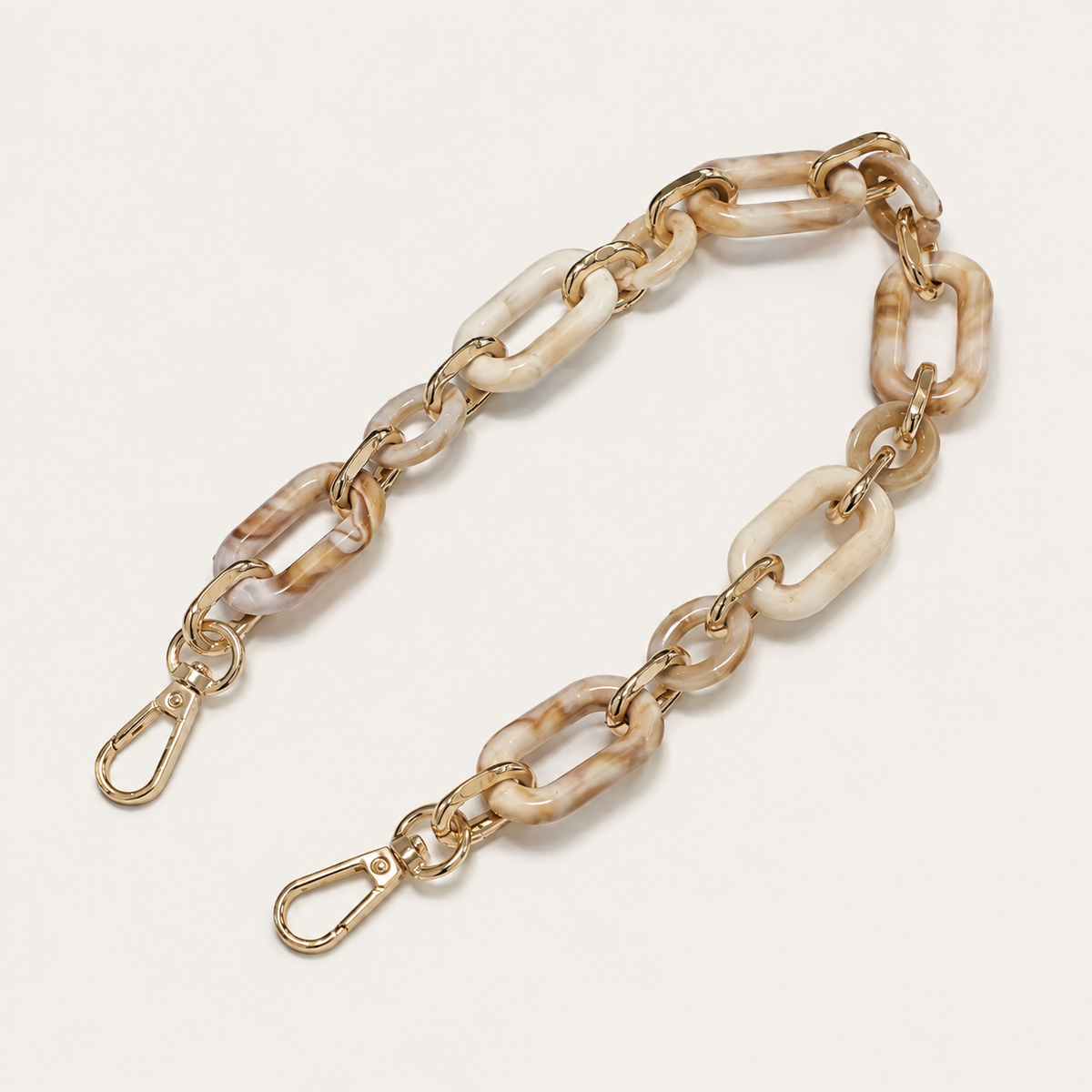 The Hazel SHORT PHONE CHAIN in cream marbled rectangular-link acrylic with gold-tone lobster clasp ends, fanned on a beige background.