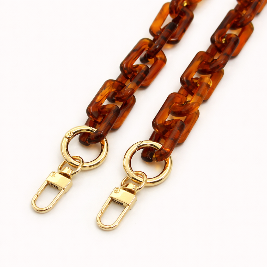 Close-up of the gold clasps on a tortoiseshell acrylic paperclip-link phone chain, shown on a white background.