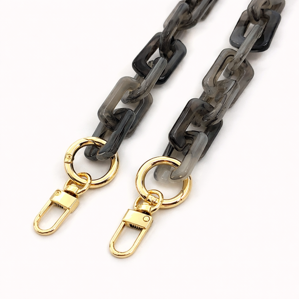 Close-up of the gold clasps on a smoky grey acrylic paperclip-link phone chain, shown on a white background.